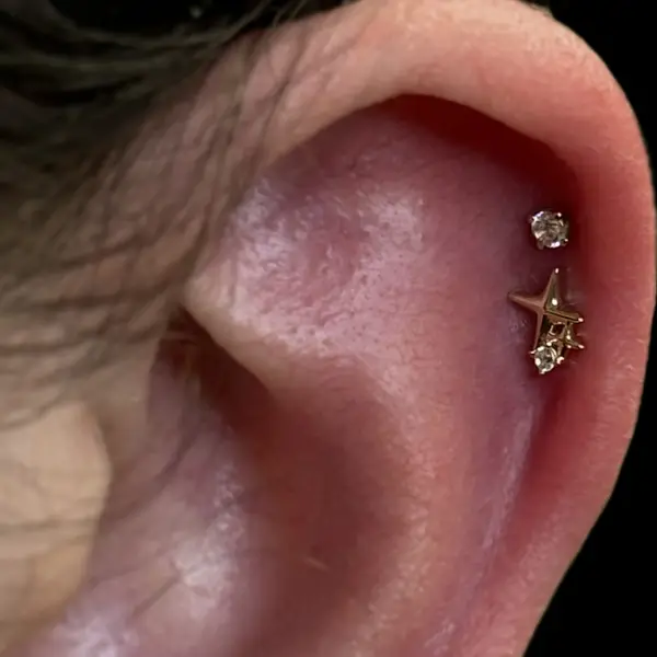 Double helix piercings with a gem stud and a gold celestial sparkle charm by T (Piercing Piranha) at Modified Tattoo Gallery in Winter Park, FL