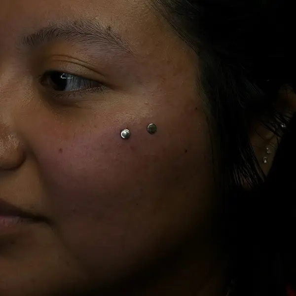 Paired cheek (dimple) piercings with silver studs by T (Piercing Piranha) at Modified Tattoo Gallery in Winter Park, FL