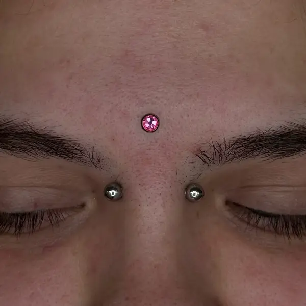 Bridge piercing with a pink gem and anti-eyebrow piercings by T (Piercing Piranha) at Modified Tattoo Gallery in Winter Park, FL