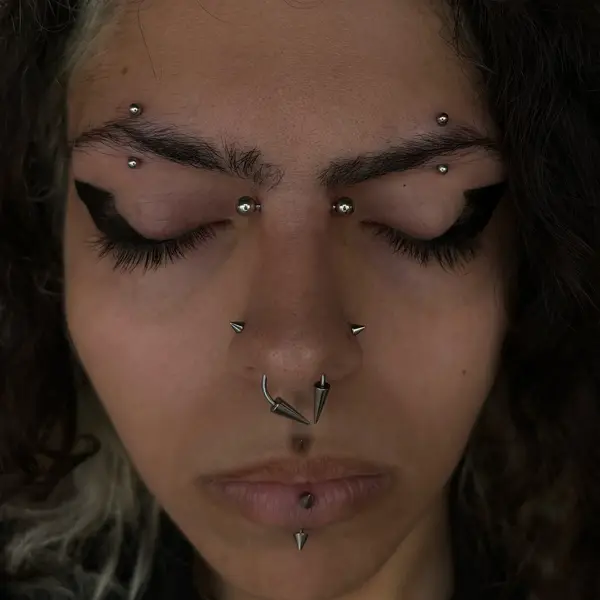 Bold spiked jewelry setup with a bridge piercing, double eyebrow piercings, a septum, and a vertical labret by T (Piercing Piranha) at Modified Tattoo Gallery in Winter Park, FL