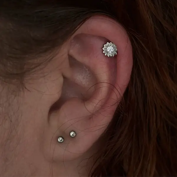Helix piercing with a flower gem charm and paired lobe studs by T (Piercing Piranha) at Modified Tattoo Gallery in Winter Park, FL