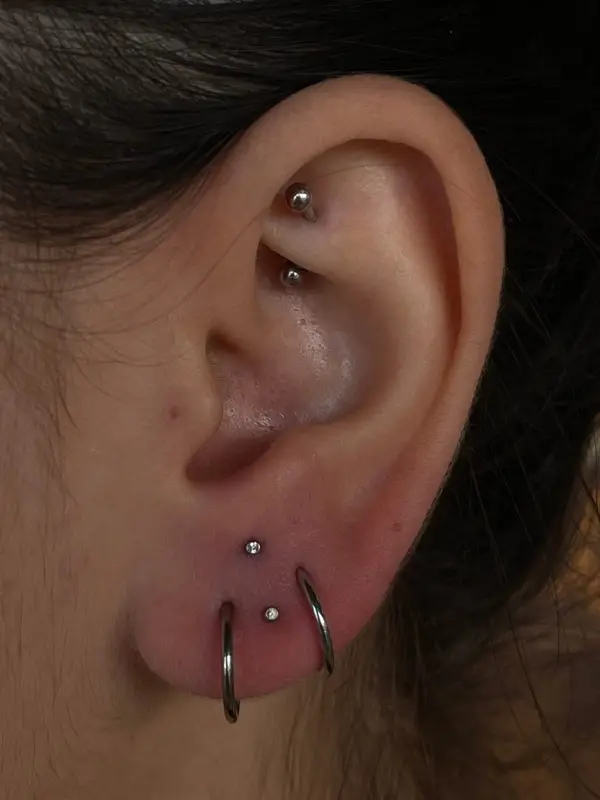 Rook piercing with a curved barbell plus stacked lobe piercings with silver hoops and a gem stud by T (Piercing Piranha) at Modified Tattoo Gallery in Winter Park, FL